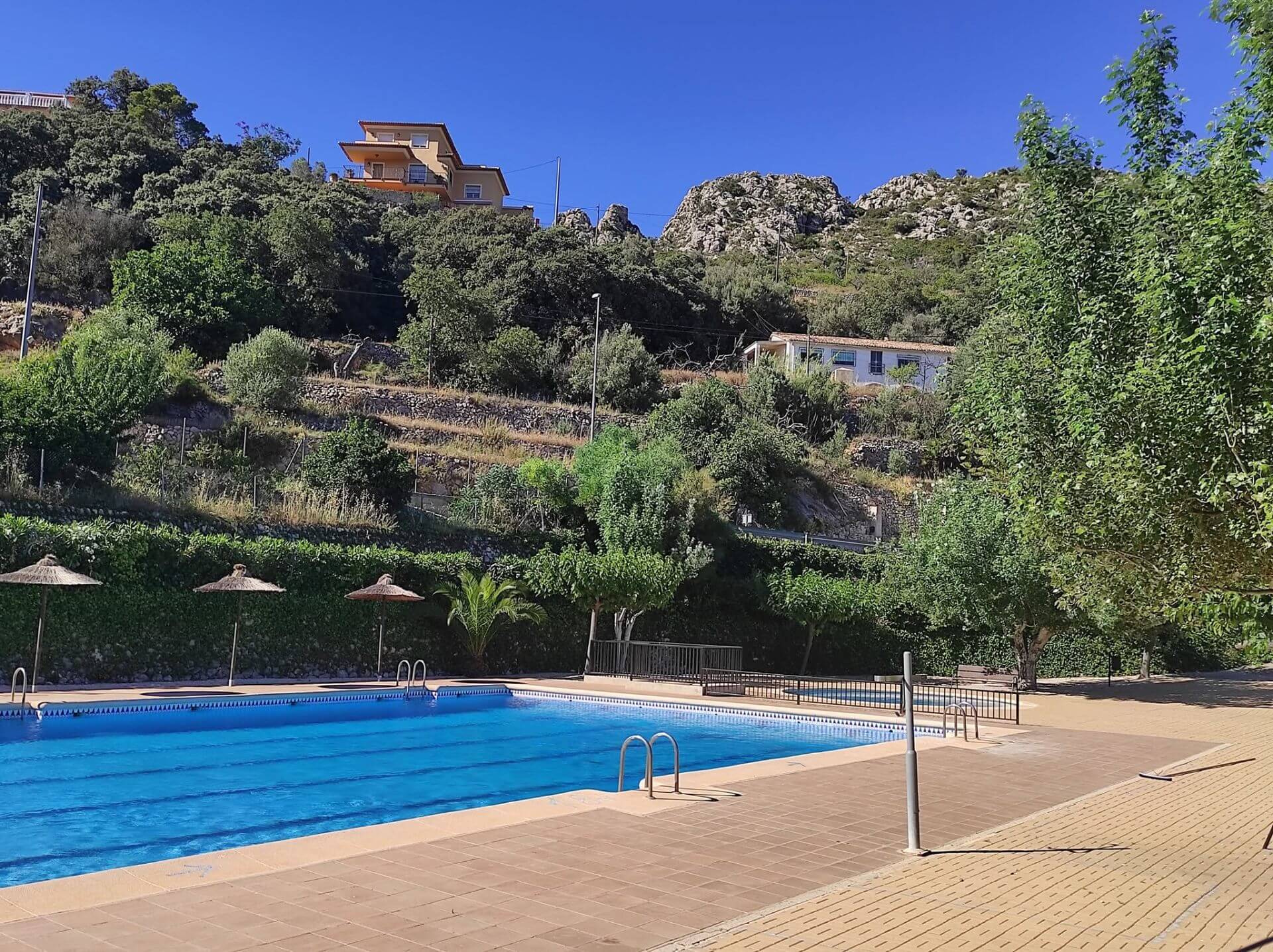 Piscine communale de Tàrbena avec transats, palmiers et vue sur la montagne